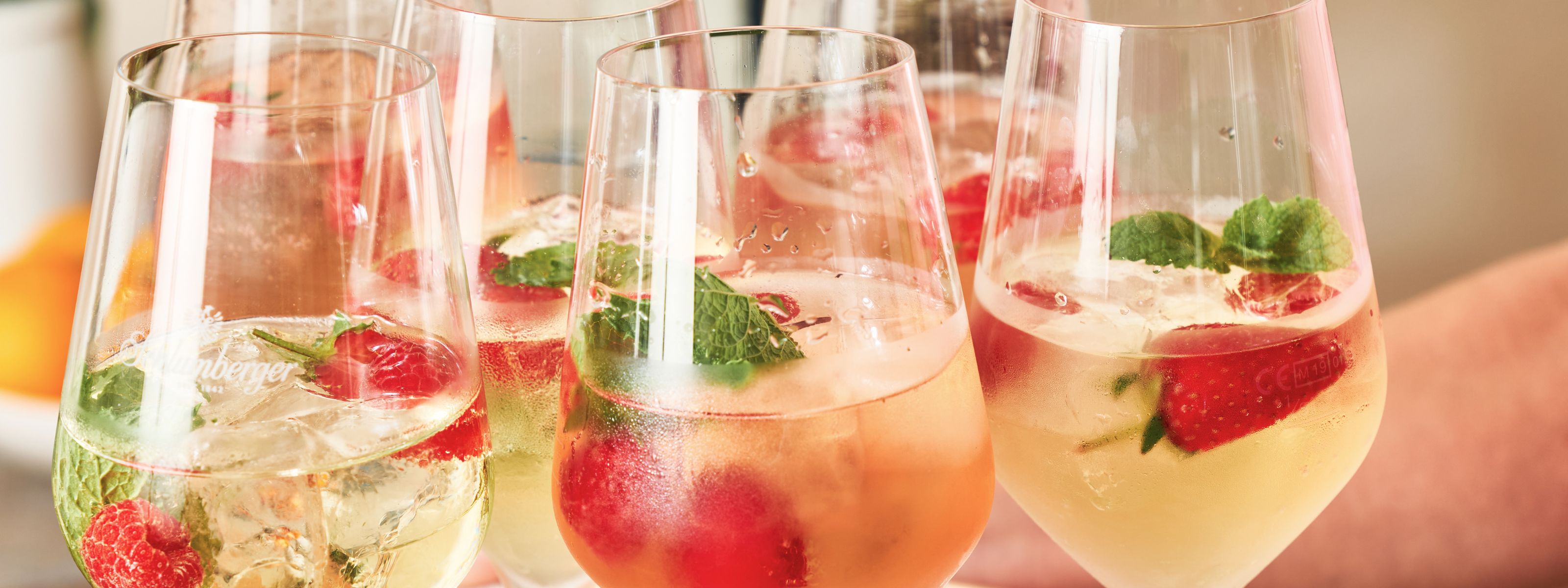 Drei Gläser gefüllt mit Sektcocktails und Früchten