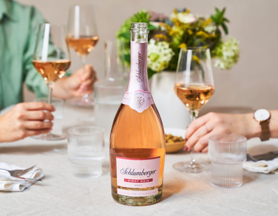 Pinot Noir Reserve steht am Tisch und drei Personen ergreifen die Gläser