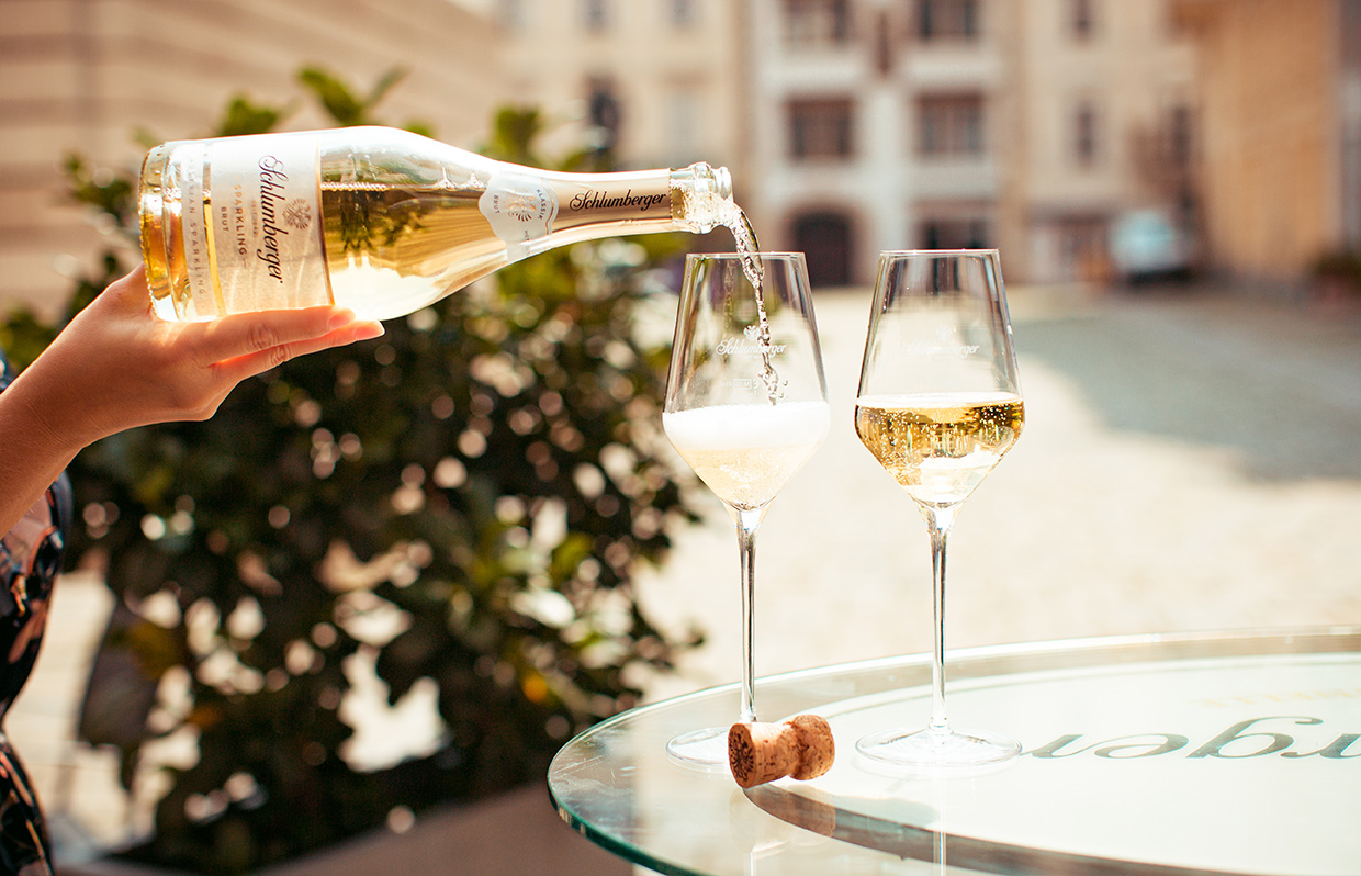 Person schenkt Schlumberger-Sekt in zwei Gläser ein