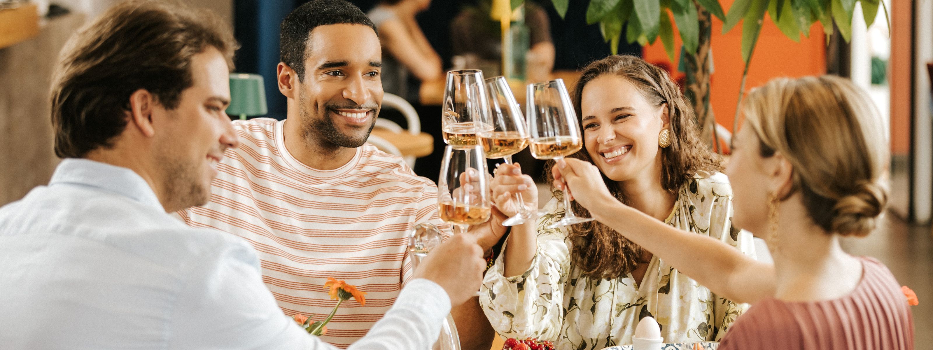 Vier Freunde stoßen mit einem Glas Rosé im Restaurant an