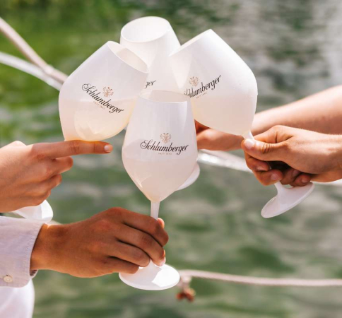 Personen stoßen mit weißen Schlumberger Gläser an 