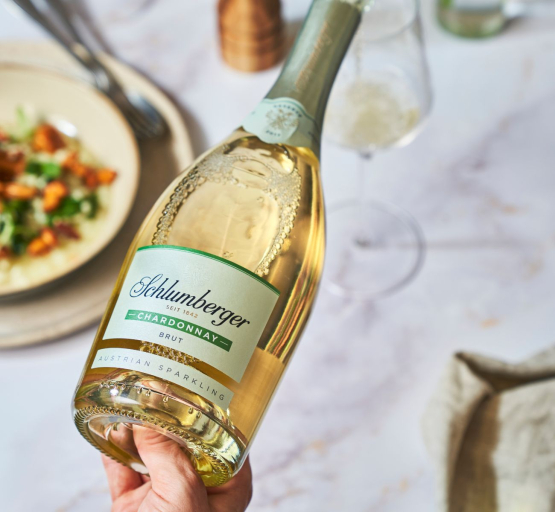 Person schenkt Chardonnay Reserve in ein Glas am gedeckten Tisch ein