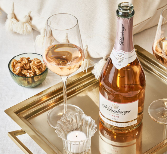 Schlumberger Rosé Brut steht auf einem Tablett und daneben ein Glas eingeschenkt mit Rosé