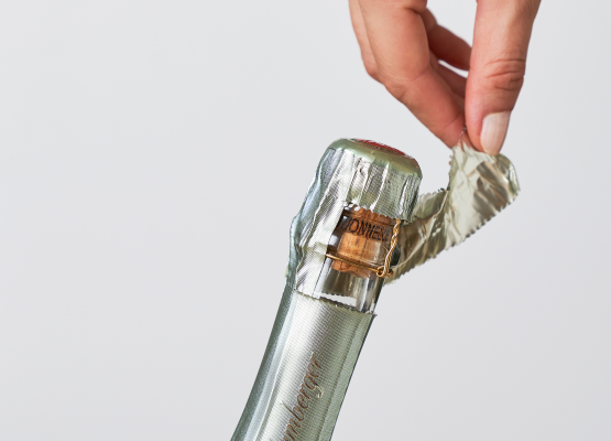 Person oeffnet Sektflasche mit spitzen Fingern