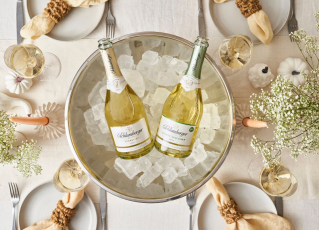 Zwei Schlumberger Flaschen liegen in einem Sektkühler mit Eiswürfel auf einem gedeckten Tisch